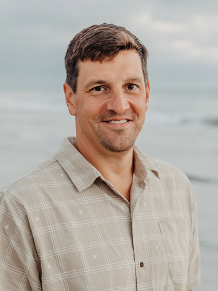 Dr. Tom Brislin, in-house oral surgeon at Bonita Family Dental in Bonita, CA, smiling in a casual outdoor portrait — a Navy veteran and Temple University oral maxillofacial surgery residency graduate serving patients throughout South San Diego
