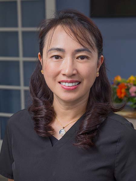 Dr. Christine Buenaventura, a dentist at Bonita Family Dental in Bonita, CA, pictured in a professional portrait wearing dental scrubs