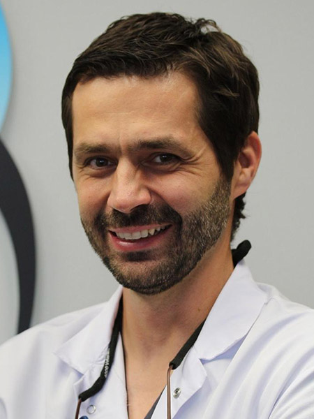 Dr. Haris Lakisic, in-house endodontist at Bonita Family Dental in Bonita, CA, wearing a white lab coat in a professional portrait — a University of Pennsylvania graduate specializing in root canal treatment for South Bay patients