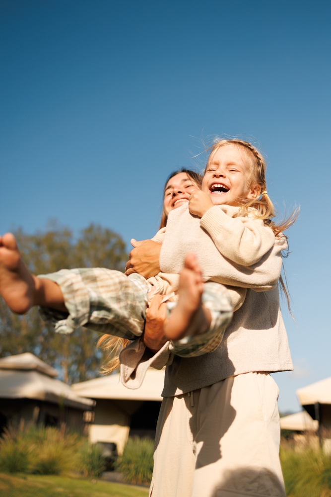 A joyful mother lifting and embracing her laughing daughter outdoors, representing the family-centered dental care provided at Bonita Family Dental for patients throughout the South Bay area